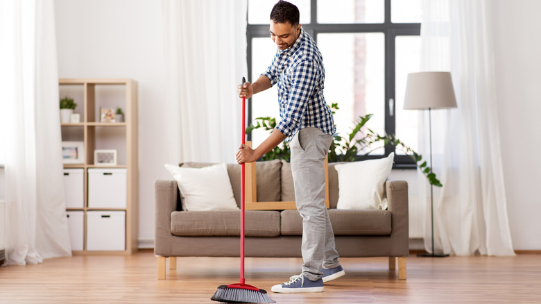 man sweeping wood floors 