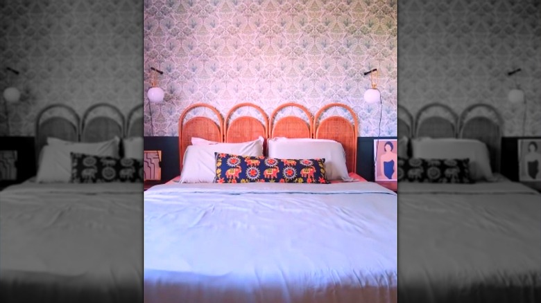 A bed with a vintage room divider as the headboard.
