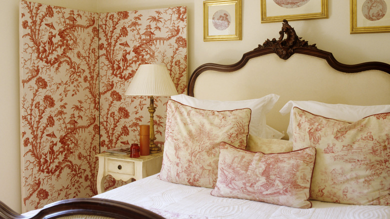 A beautiful antique bedroom set with a ornately painted divider screen in the corner.