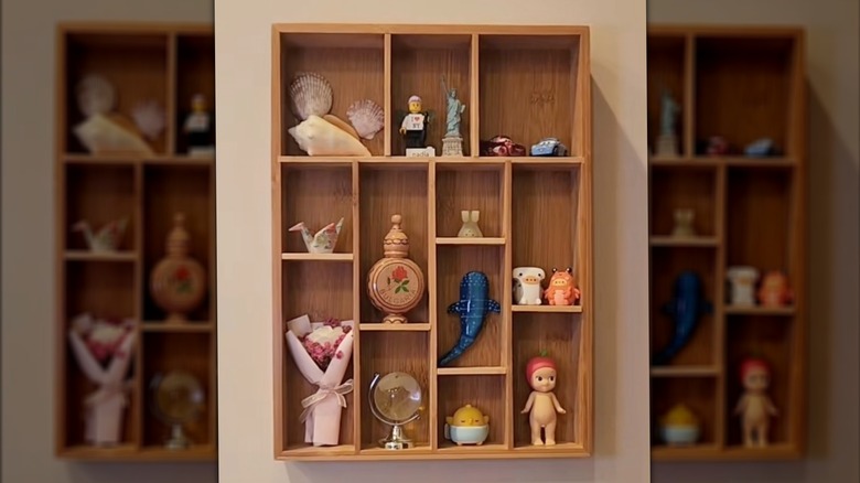 A bamboo utensil tray displays knickknacks, including a shell, paper crane, baby doll, and animal figurines.