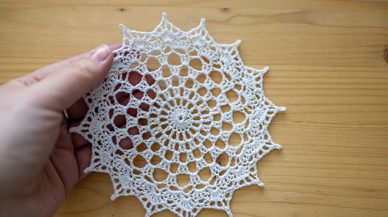 A woman holding a white crochet doily