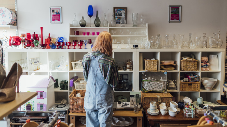 Woman shopping at a thrift store, in the miscellaneous section