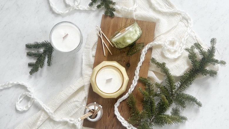 Candles made in vintage-inspired heat-safe jars sit on a decorated tabletop.