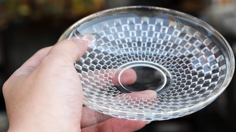 Person holds a small crystal glass dish
