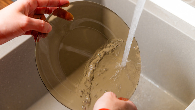 Person rinses a transluscent brown glass plate