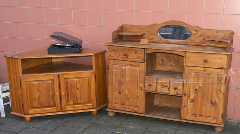 Orange oak freestanding cabinets against pink tile wall.