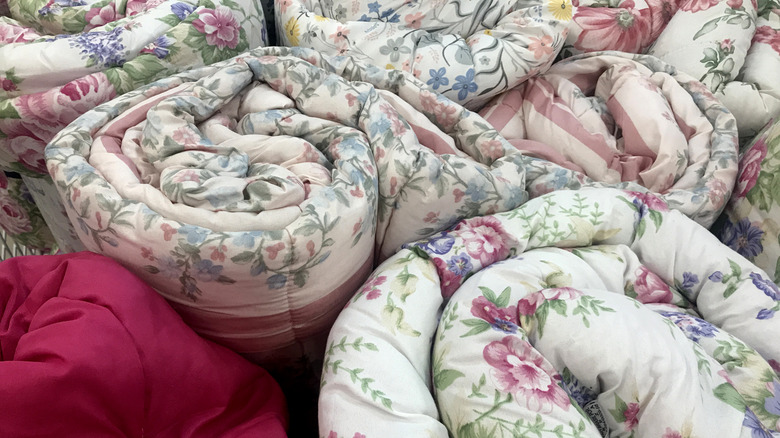 Several floral bedspreads coiled and stacked next to each other