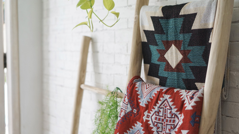 Two patterned blankets hanging from wooden ladder