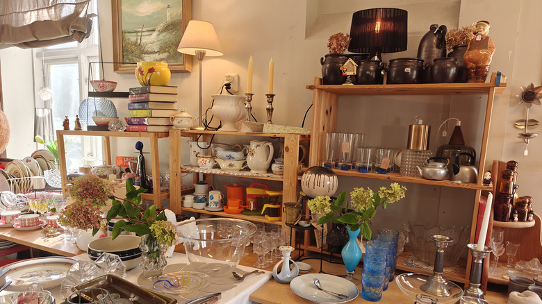 Full shelves of kitchen crockery and decor in thrift store