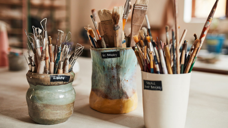 Handmade ceramic vases holding paintbrushes and clay tools