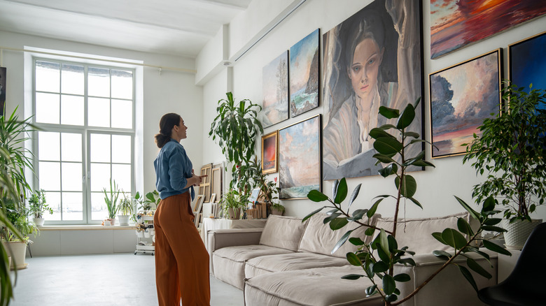 Woman looking at a wall of art in a living room
