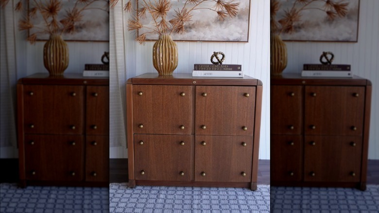 A DIY wooden dresser with flowers in a vase on it and a picture in the background