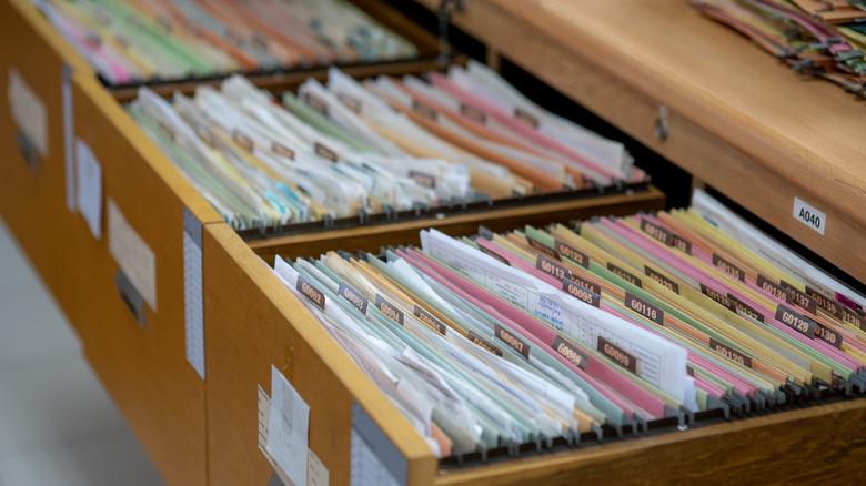 A wooden filing cabinet filled with files