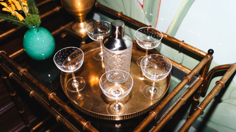 Vintage bar cart featuring a brassy finish with glassware and a vase on top
