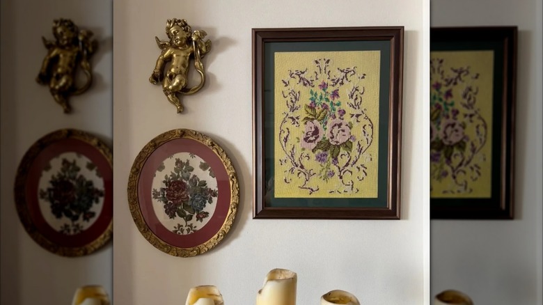Two framed floral pillow cases on a wall behind decorative candles