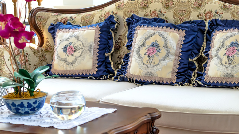 three vintage pillow covers with florals and blue ruffles on a couch