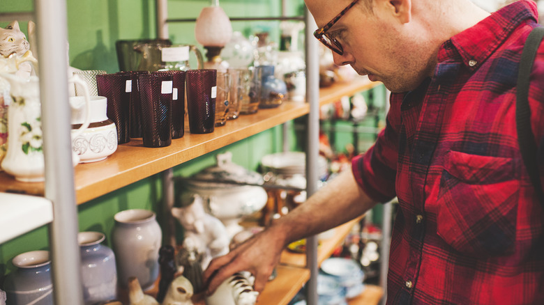A man reaching for a ceramic item at a thrift store
