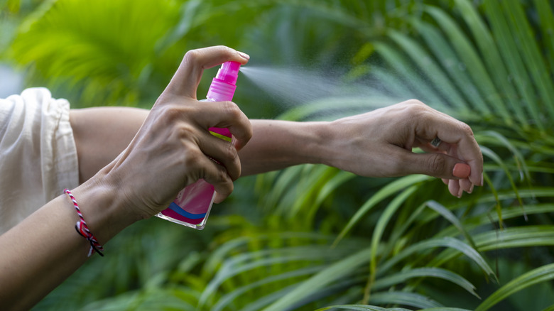 A female is spraying an insect repellent on her arm