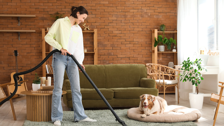 woman vacuuming home with dog