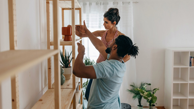 A couple organizing open shelving