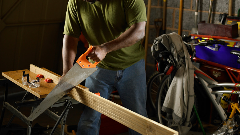 Man sawing wood in workshop