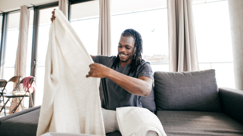 man holding sheet on sofa 