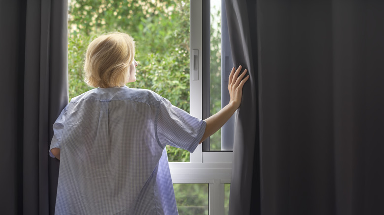 Woman standing in window curtains