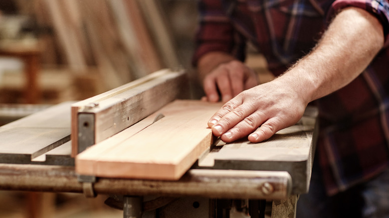 slicing wood plank with saw 