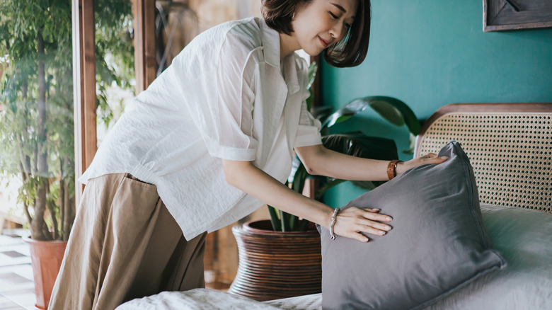 woman making bed pillow 