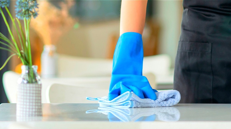 Person with gloves cleaning table
