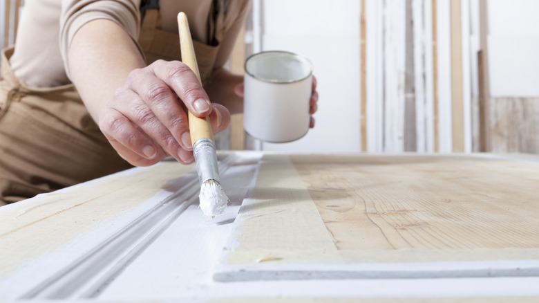 woman painting door white 