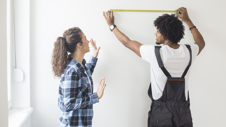 couple measuring wall