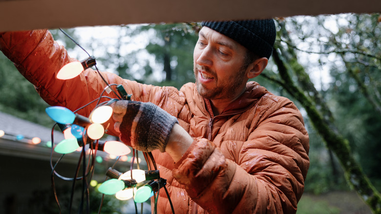 Man hanging string lights on gutter