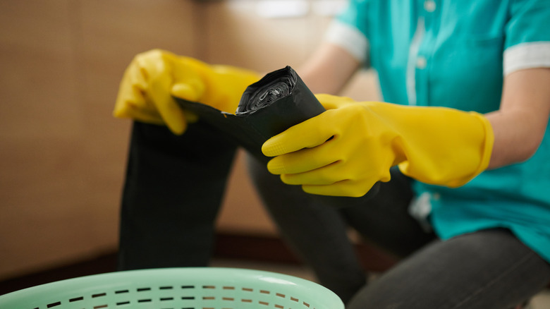 person removing trash bag from roll