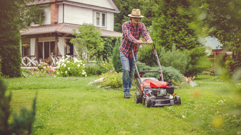 Man mows lawn outside house