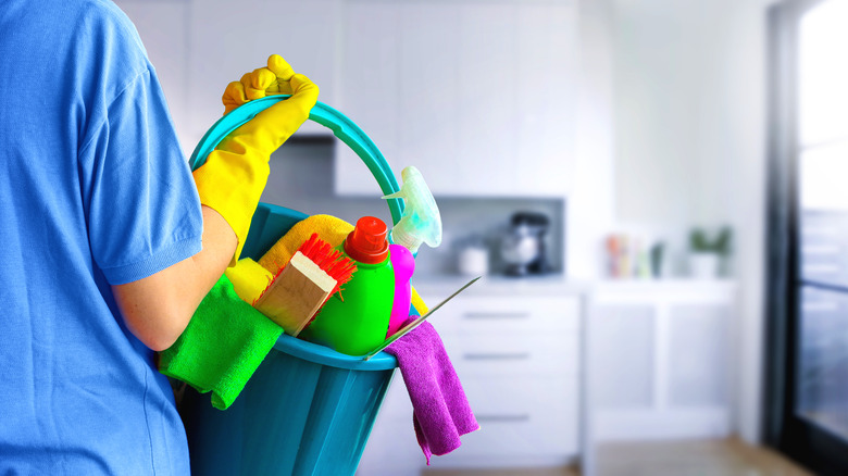 Person holding colorful cleaning supplies