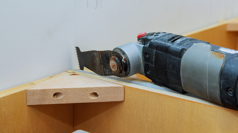 person using oscillating tool on wood