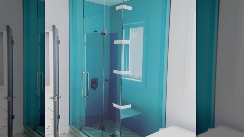 A shower that includes teal back painted glass on the walls