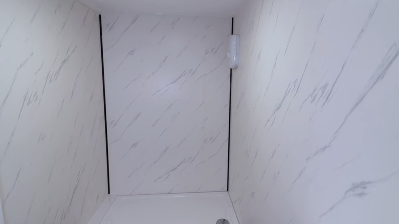 A shower with wall panels covered with stone-look PVC