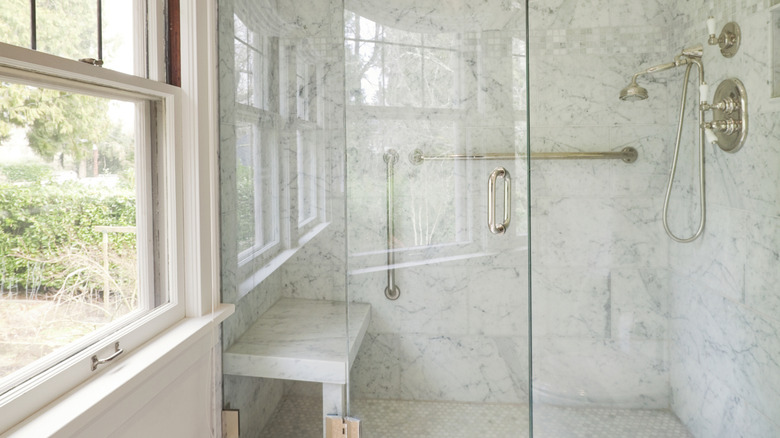 A shower with walls covered in white marble stone