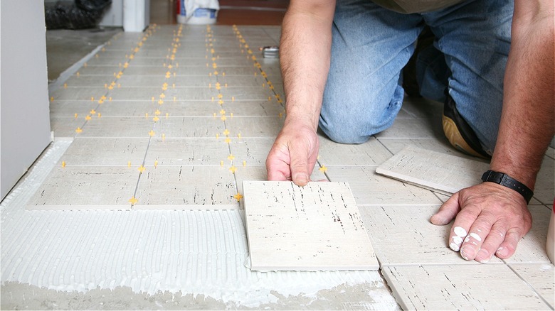 Person installing floor tiles