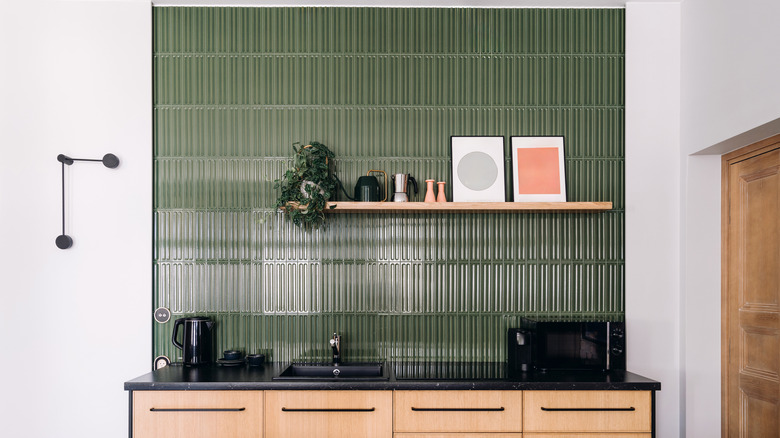 A kitchen with ceiling-height backsplash in green, textured, high-gloss, vertical tiles