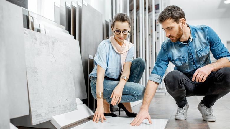 Young couple choosing big granite tiles for their house