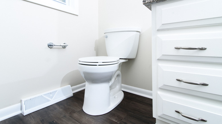 white bathroom with laminate flooring and wood baseboards