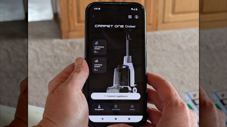 A light-skinned person's hands hold a phone with the Tineco app open.