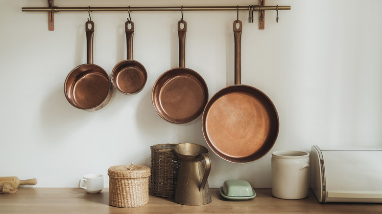 Copper pots hanging from kitchen rail