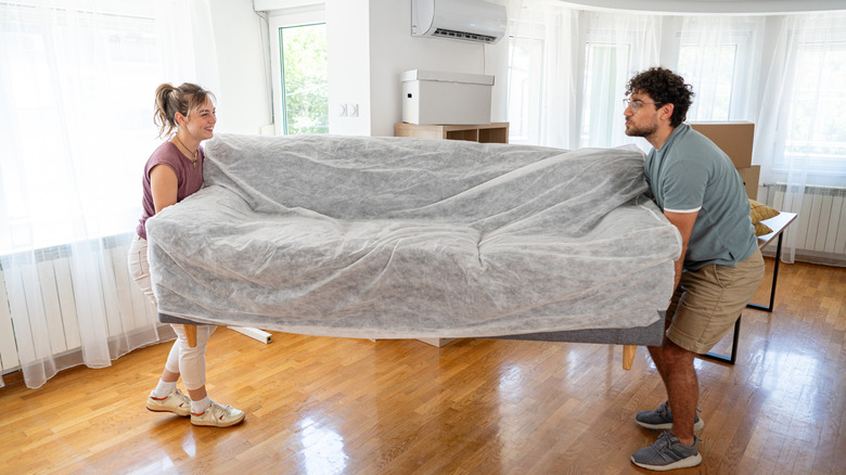 A couple works together to move a sofa into a new apartment