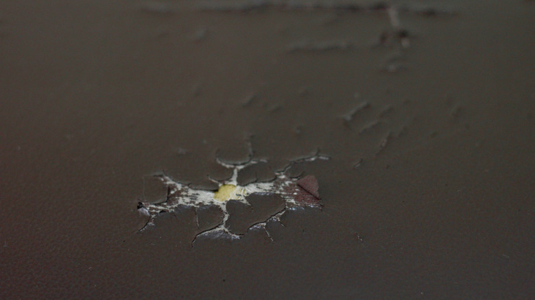A hole and some cracks on brown leather furniture