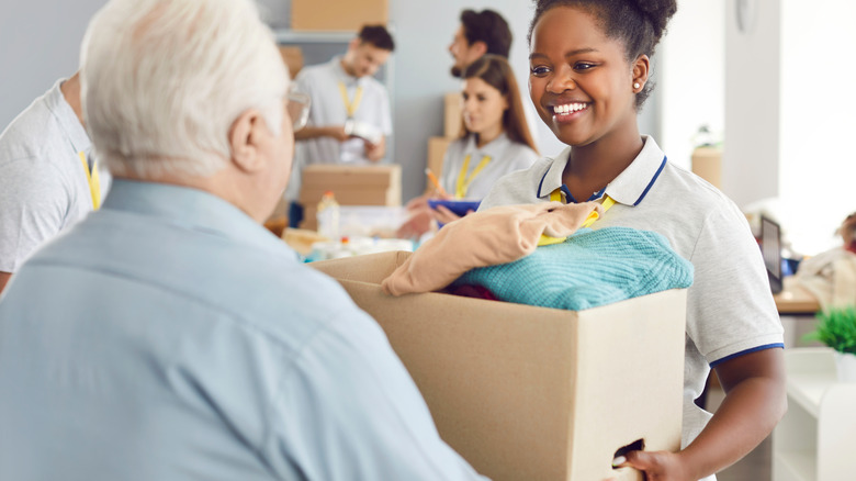 Man handing clothes-filled cardboard box to charity worker