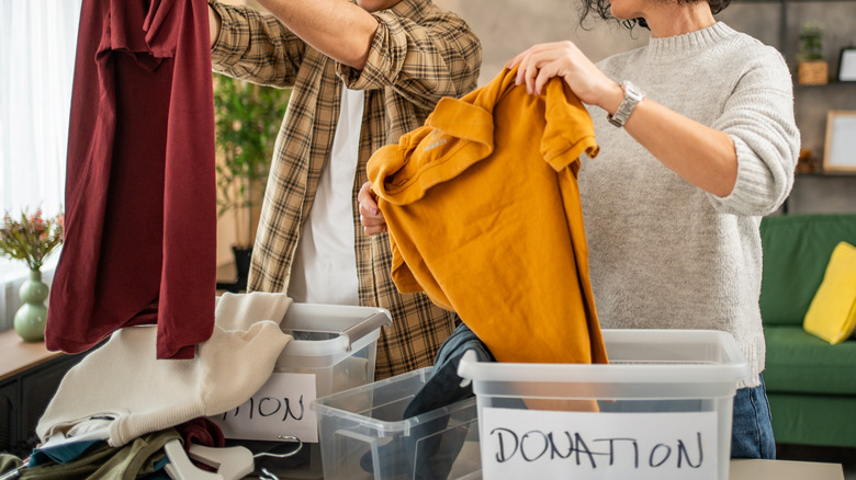 A man and a woman putting clothes in cardboard boxes labelled "donate"